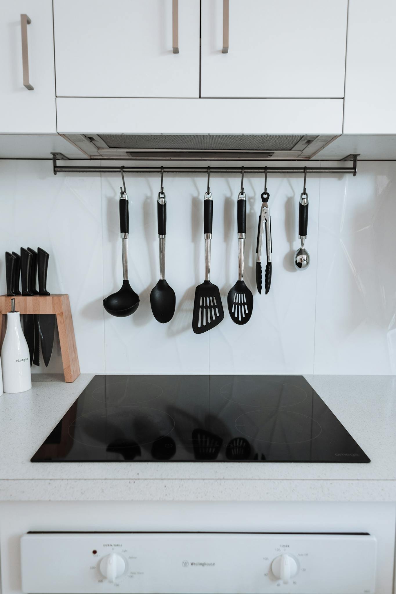 A sleek kitchen interior with hanging stainless steel utensils over an induction stove.